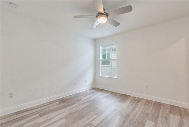 spare room featuring baseboards, ceiling fan, and light wood-style flooring