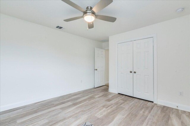 unfurnished bedroom featuring light wood-type flooring, baseboards, visible vents, and a closet