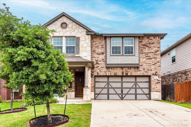 view of front of home featuring a garage, fence, stone siding, a front yard, and driveway