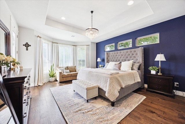 bedroom featuring a tray ceiling, dark wood-style floors, and multiple windows