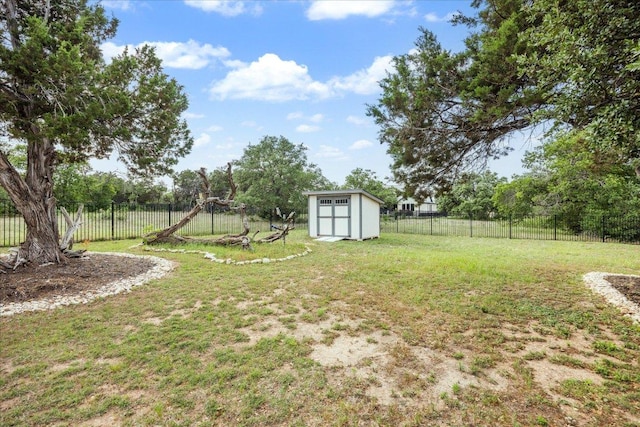 view of yard with a storage unit, a fenced backyard, and an outbuilding