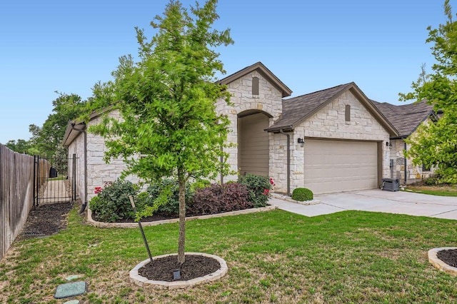 view of front of home featuring driveway, a front yard, a garage, fence, and stone siding