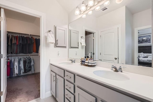 full bath featuring double vanity, a walk in closet, visible vents, and a sink