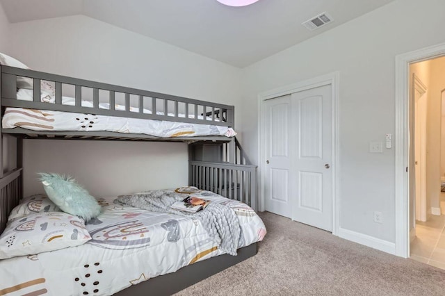 carpeted bedroom featuring visible vents, vaulted ceiling, and a closet