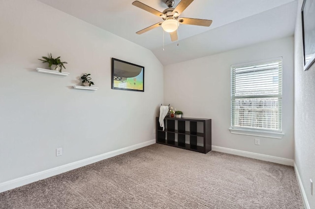 carpeted spare room featuring baseboards, a ceiling fan, and lofted ceiling