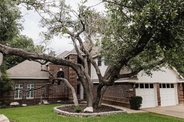 view of front of property featuring a shingled roof, concrete driveway, a front yard, and brick siding