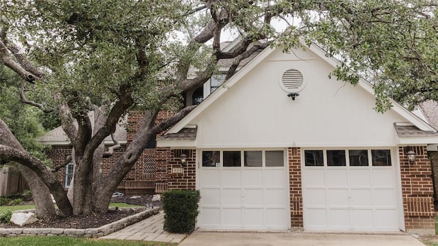 view of front of house with a garage, a shingled roof, concrete driveway, and brick siding