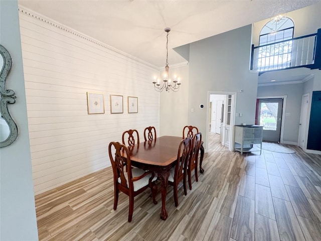dining area with a high ceiling, a chandelier, and wood finished floors
