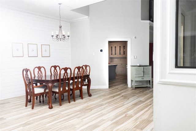 dining space with crown molding, baseboards, light wood-style flooring, and a notable chandelier
