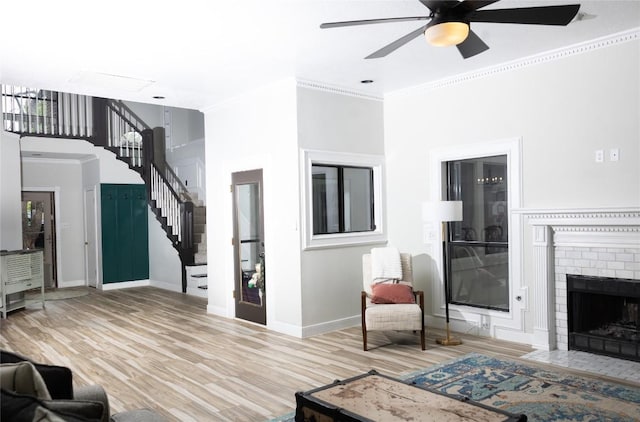 living area with ceiling fan, stairs, baseboards, wood finished floors, and ornamental molding