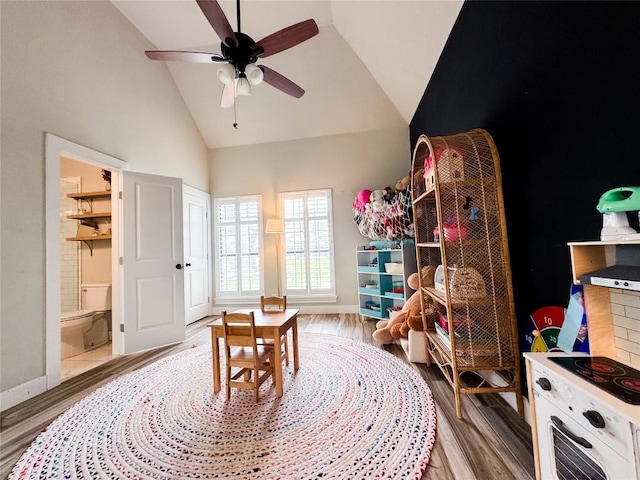 playroom with baseboards, a ceiling fan, wood finished floors, and high vaulted ceiling