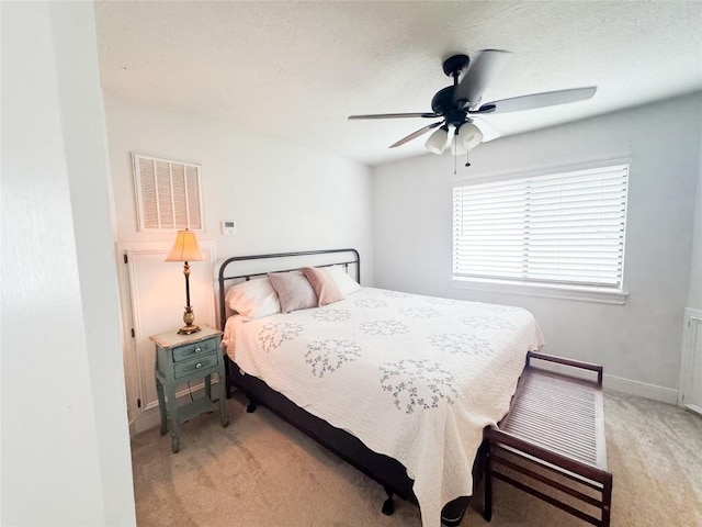 bedroom with visible vents, baseboards, ceiling fan, and light carpet