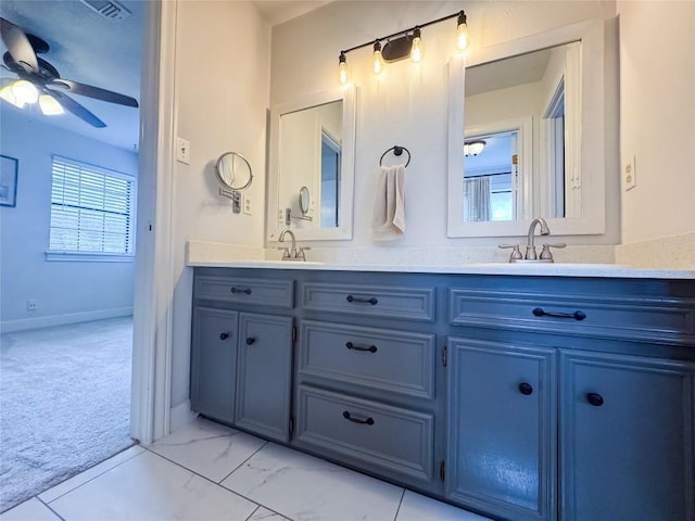 bathroom with baseboards, double vanity, a ceiling fan, and a sink