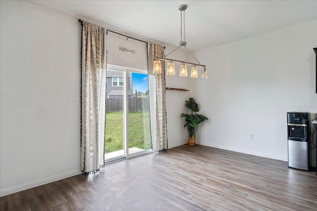 unfurnished dining area featuring baseboards, plenty of natural light, and wood finished floors