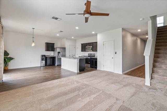 unfurnished living room with ceiling fan, visible vents, a sink, baseboards, and recessed lighting
