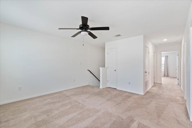 spare room featuring baseboards, light carpet, a ceiling fan, and visible vents