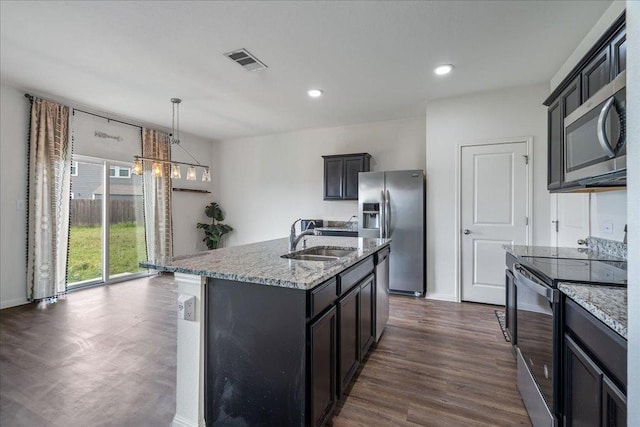 kitchen with light stone countertops, a sink, dark wood finished floors, stainless steel appliances, and visible vents