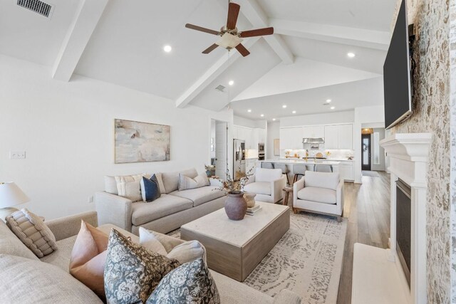living room with light wood-style floors, a ceiling fan, recessed lighting, beamed ceiling, and visible vents