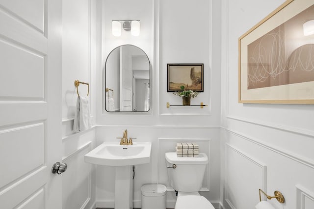 half bathroom featuring toilet and a decorative wall