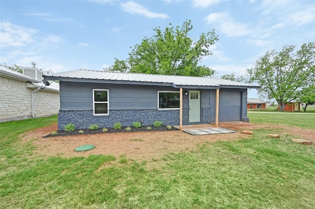 view of front of property with metal roof, an attached garage, a front lawn, and stone siding