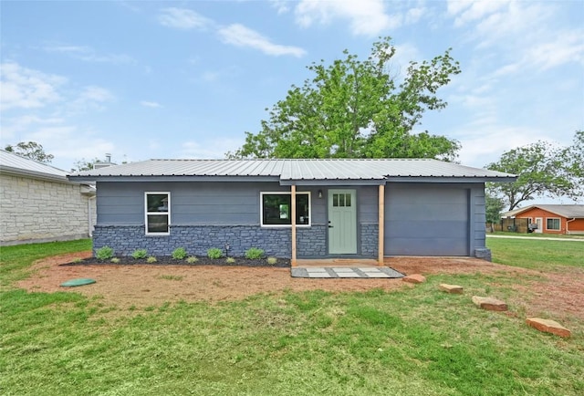single story home featuring metal roof, an attached garage, a front lawn, and stone siding