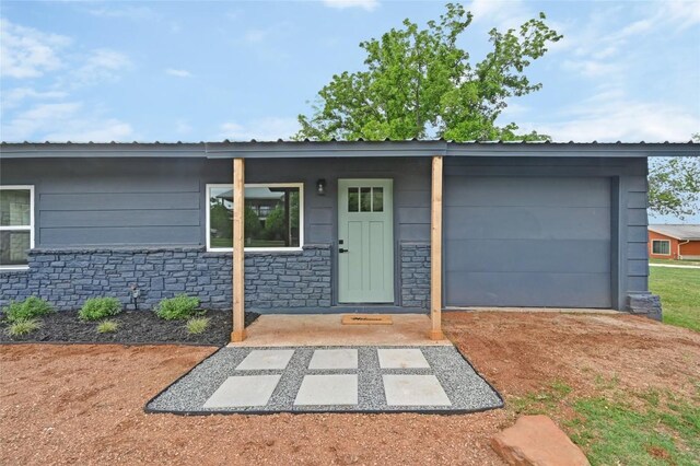 view of front of property with an attached garage and stone siding