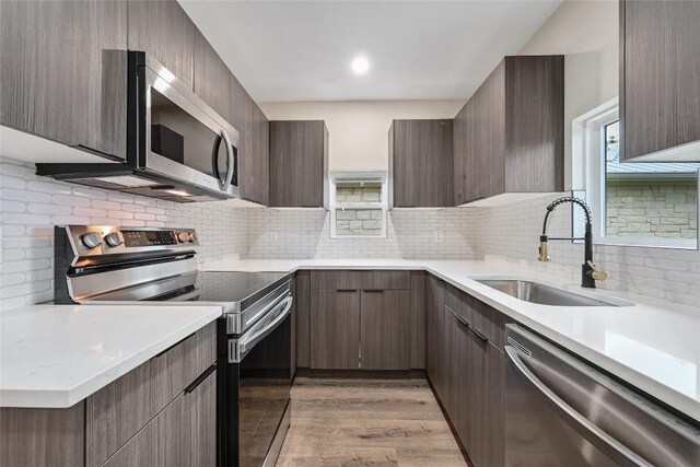 kitchen featuring a sink, modern cabinets, backsplash, and stainless steel appliances