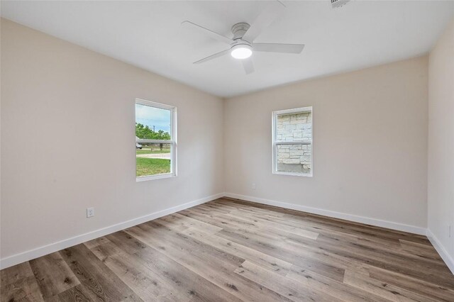empty room with baseboards, a ceiling fan, and wood finished floors