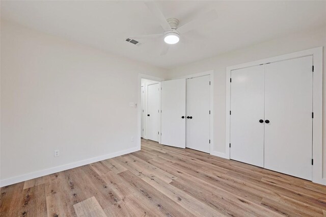 unfurnished bedroom with ceiling fan, visible vents, baseboards, two closets, and light wood-style flooring