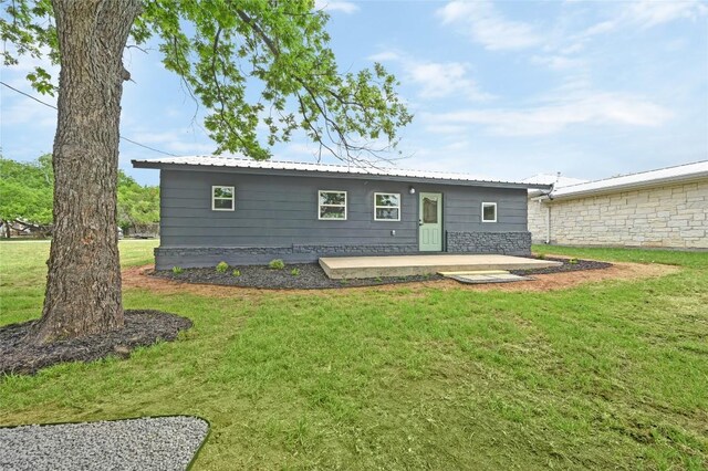rear view of property featuring a patio area, a yard, and metal roof