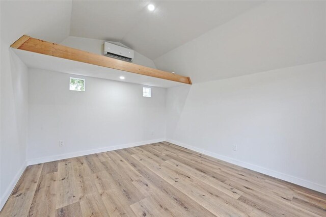 interior space featuring vaulted ceiling, a wall mounted air conditioner, wood finished floors, baseboards, and recessed lighting