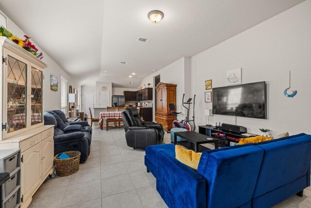 living area featuring visible vents, light tile patterned floors, and lofted ceiling