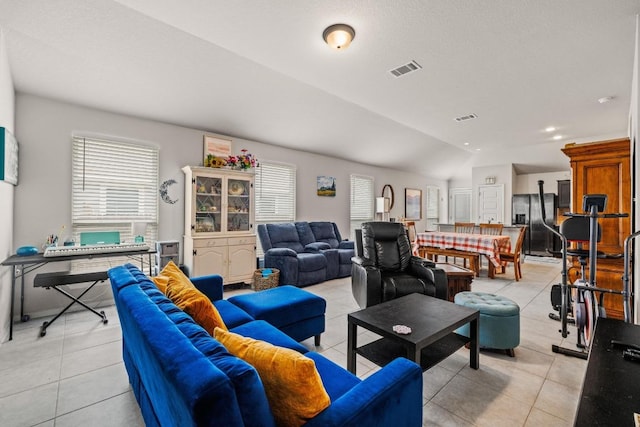 living area featuring visible vents, light tile patterned floors, and lofted ceiling