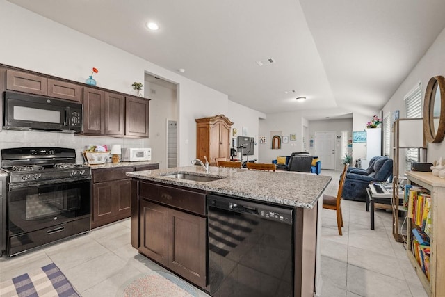 kitchen with a sink, light tile patterned floors, black appliances, and open floor plan