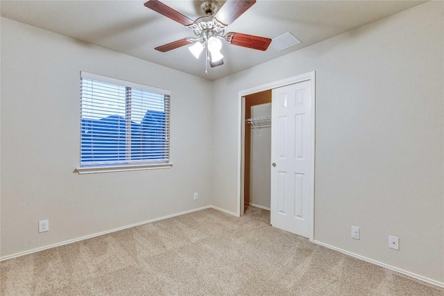 unfurnished bedroom featuring visible vents, carpet floors, a closet, baseboards, and a ceiling fan