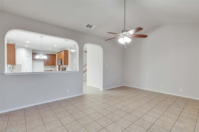 unfurnished living room featuring visible vents, arched walkways, ceiling fan with notable chandelier, and vaulted ceiling