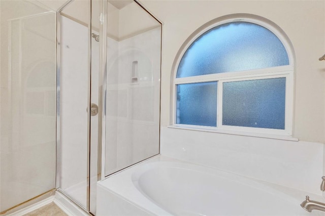 full bathroom featuring plenty of natural light, a bath, and a stall shower