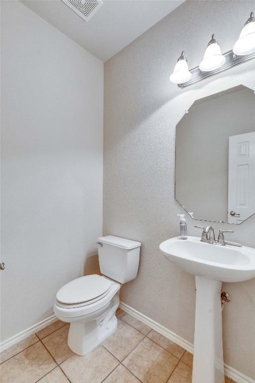 half bath with baseboards, tile patterned flooring, toilet, and visible vents
