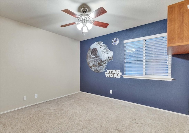 empty room with carpet flooring, ceiling fan, and baseboards