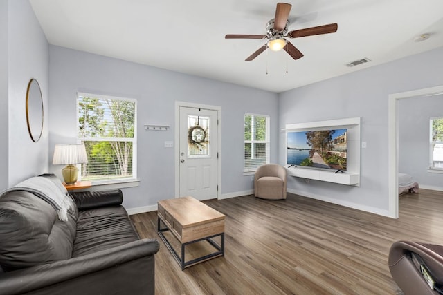 living room featuring visible vents, baseboards, wood finished floors, and a healthy amount of sunlight