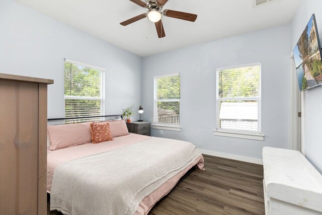 bedroom with a ceiling fan, baseboards, multiple windows, and wood finished floors