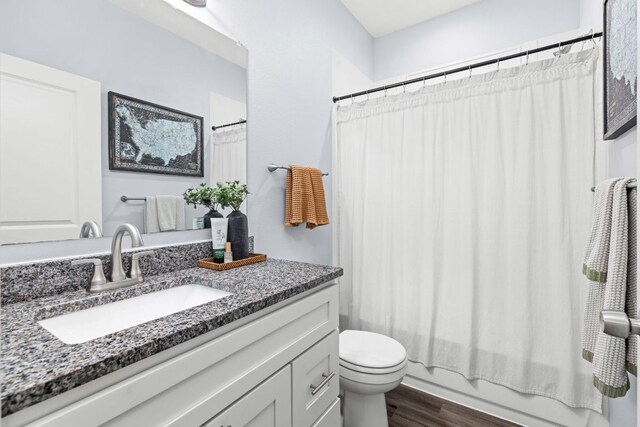 full bath featuring toilet, shower / bathtub combination with curtain, wood finished floors, and vanity