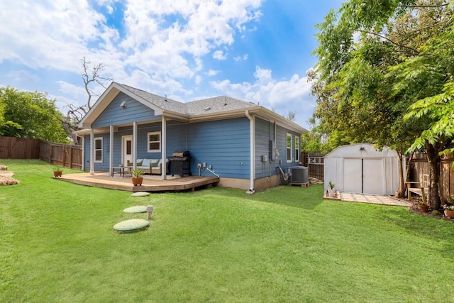 rear view of property featuring a fenced backyard, a wooden deck, a yard, and a storage shed