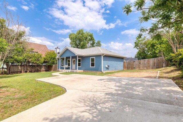 rear view of property with a porch, a lawn, fence, and driveway