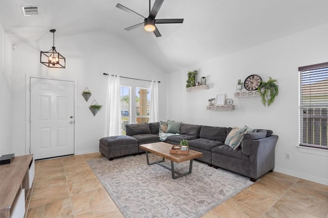 living area featuring high vaulted ceiling, baseboards, ceiling fan with notable chandelier, and visible vents