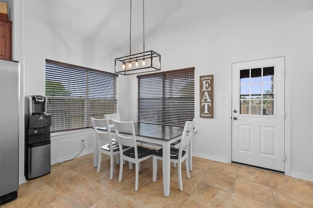 dining space featuring baseboards, a healthy amount of sunlight, and high vaulted ceiling