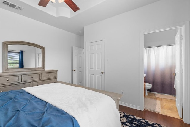 bedroom with connected bathroom, ceiling fan, baseboards, wood finished floors, and visible vents