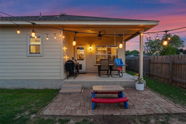 patio terrace at dusk featuring a ceiling fan and a fenced backyard