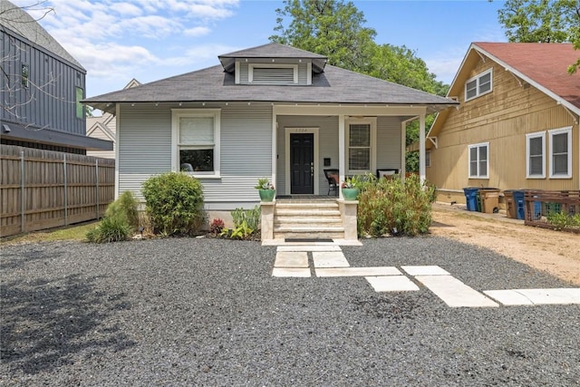 bungalow-style house featuring a shingled roof, fence, and covered porch