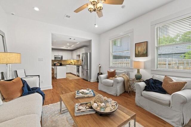 living area featuring visible vents, baseboards, recessed lighting, light wood-type flooring, and a ceiling fan